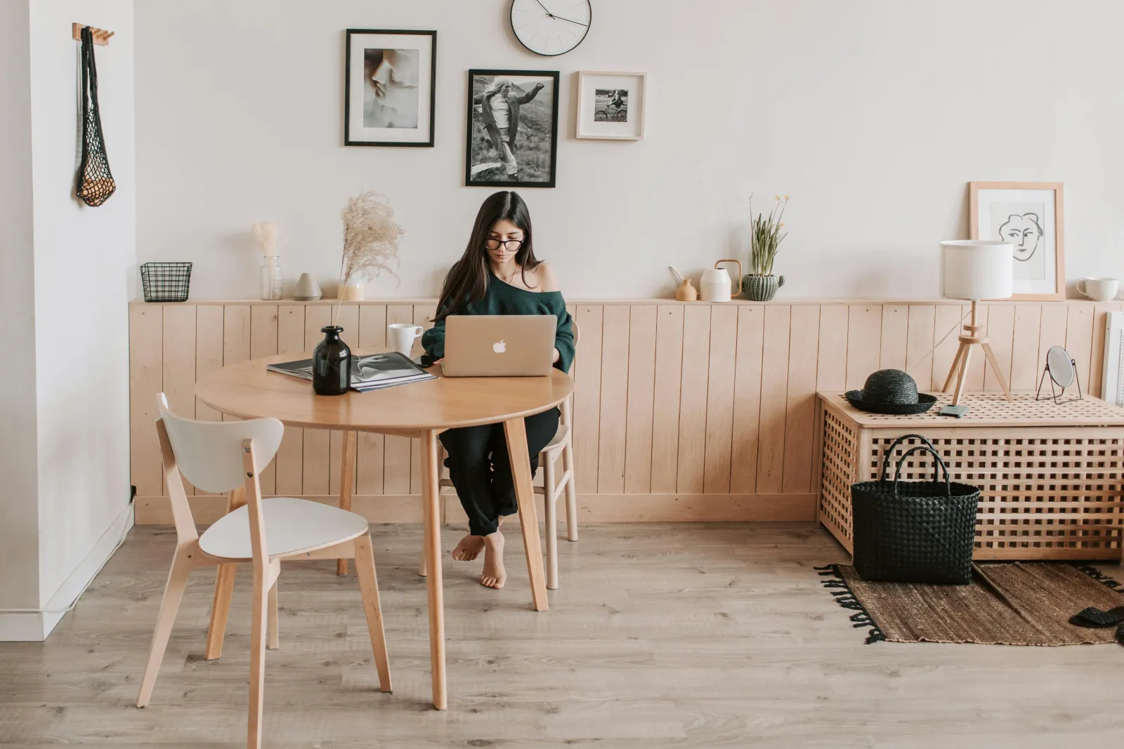Kvinne ved en laptop på et minimalistisk hjemmekontor med trebord